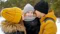 Mom and dad are cuddling and kissing their little son in winter park. Royalty Free Stock Photo