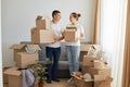 Portrait of happy family, woman and man wearing white t shirts standing with cardboard boxes, relocating to a new house, unpacking Royalty Free Stock Photo