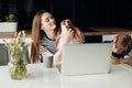 Portrait of happy family. Young woman sitting at table with little boy son, holding stroking spaniel, working on laptop.