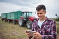 Portrait of happy farmer holding tablet standing in front of tractor with trailer Royalty Free Stock Photo