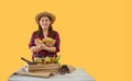 Portrait of happy farmer woman standing holding fresh cacao fruit and looking at camera with isolated on yellow background Royalty Free Stock Photo