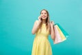 Portrait of happy fashion caucasian woman with shopping bags calling on mobile phone. on blue background. Royalty Free Stock Photo