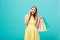 Portrait of happy fashion caucasian woman with shopping bags calling on mobile phone. Isolated on blue background. Royalty Free Stock Photo