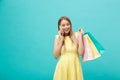 Portrait of happy fashion caucasian woman with shopping bags calling on mobile phone. Isolated on blue background. Royalty Free Stock Photo