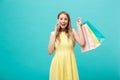 Portrait of happy fashion caucasian woman with shopping bags calling on mobile phone. Isolated on blue background. Royalty Free Stock Photo