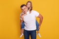 Portrait of happy father and beautiful little girl wering white t shirts and jeans, posing isolated over yellow studio background