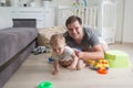 Portrait of happy father crawling with his baby boy on floor at Royalty Free Stock Photo