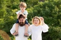 Portrait of happy father giving son piggyback ride on his shoulders and looking up. Summer ration. Happy family smiling Royalty Free Stock Photo