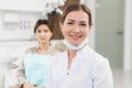 A portrait of a happy female dentist wearing lab coat, while sitting in her office Royalty Free Stock Photo