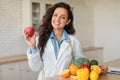 Portrait of happy female dietologist holding apple, recommending fresh fruits and vegetables, copy space Royalty Free Stock Photo