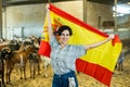 Portrait of happy female farmer with spanish flag in their hands in goat pen Royalty Free Stock Photo