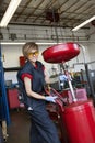 Portrait of a happy female mechanic working on welding equipment in garage