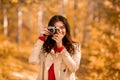 Portrait of happy female photographer with retro camera taking pictures of beautiful autumn at park Royalty Free Stock Photo