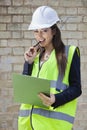 Portrait of a happy female supervisor with clipboard standing at construction site Royalty Free Stock Photo