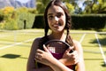 Portrait of happy fit caucasian woman holding tennis racket on sunny outdoor tennis court Royalty Free Stock Photo