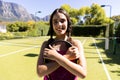 Portrait of happy fit caucasian woman holding tennis racket on sunny outdoor tennis court Royalty Free Stock Photo