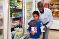 Portrait of happy friendly African family of father and tween son shopping in supermarket Royalty Free Stock Photo