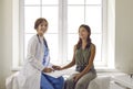 Happy doctor and a child patient sitting on a medical couch, holding hands and smiling Royalty Free Stock Photo