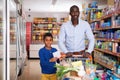 Portrait of happy friendly African family of father and tween son shopping in supermarket Royalty Free Stock Photo