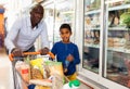 Portrait of happy friendly African family of father and tween son shopping in supermarket Royalty Free Stock Photo