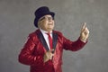 Funny senior man in retro party outfit dancing and having fun on gray studio background Royalty Free Stock Photo