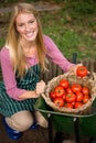 Portrait of happy gardener looking at fresh tomatoes in basket at garden