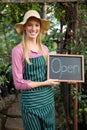 Portrait of happy gardener with open text on chalkboard at garden