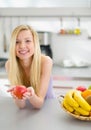 Portrait of happy girl with apple in kitchen Royalty Free Stock Photo