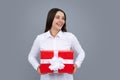 Portrait of a happy girl with gift box isolated over gray background. Woman holding gift present. Royalty Free Stock Photo