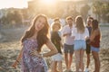 Happy girl with hand on hip standing on beach with friends Royalty Free Stock Photo