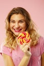 Portrait of a happy pretty girl holding sweet candy over pink ba Royalty Free Stock Photo