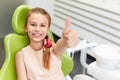 Portrait of happy girl shows thumb up gesture at dental clinic Royalty Free Stock Photo