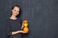 Portrait of happy girl smiling and holding colorful stack of fruits