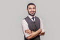 Portrait of happy glad handsome bearded brunette man in white shirt, waistcoat standing, crossed arms, looking at camera with Royalty Free Stock Photo