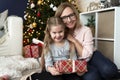 Portrait of grandma and granddaughter embracing beside a Christmas tree Royalty Free Stock Photo