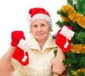 Portrait of happy grandma in Santa cap decorating Christmas tree