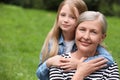 Portrait of happy grandmother hugging her granddaughter outdoors, space for text Royalty Free Stock Photo