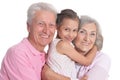 Portrait of happy grandparents with granddaughter posing on white background