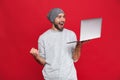 Portrait of happy guy rejoicing while holding silver laptop isolated over red background