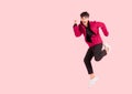 Portrait of happy handsome Asian man in a pink jacket excited and celebrating by jumping up in the air with winner gesture Royalty Free Stock Photo