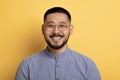 Portrait of happy handsome asian man posing on yellow studio background Royalty Free Stock Photo