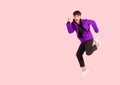 Portrait of happy handsome Asian man in purple jacket excited and celebrating by jumping up in the air with winner gesture Royalty Free Stock Photo