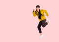 Portrait of happy handsome Asian man in yellow jacket excited and celebrating by jumping up in the air with winner gesture