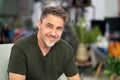 Portrait of happy handsome attractive mature man with beard looking at camera indoor at home in the living room Royalty Free Stock Photo