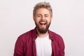 Portrait of happy handsome bearded young man in plaid shirt sincerely laughing with open mouth Royalty Free Stock Photo