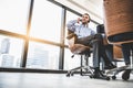 Portrait of happy handsome business man with headset in modern office with city urban building background. Businessman sitting on Royalty Free Stock Photo