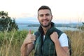 Portrait of a happy handsome man with backpack hiking into the forest with stunning view from a top of a mountain Royalty Free Stock Photo