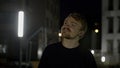 Portrait of a happy handsome man looking around in a dark street. Media. Male model posing on camera outside the Royalty Free Stock Photo