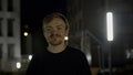 Portrait of a happy handsome man winks at camera in a dark street. Media. Male model posing on camera outside the Royalty Free Stock Photo