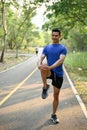 Happy Asian man in sportswear stretching his leg on a street before running Royalty Free Stock Photo